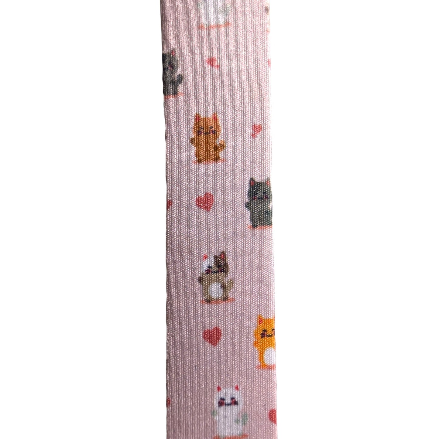 A close-up vertical view of a light pink fabric strap or band printed with small cartoon cats and red hearts on a white background.