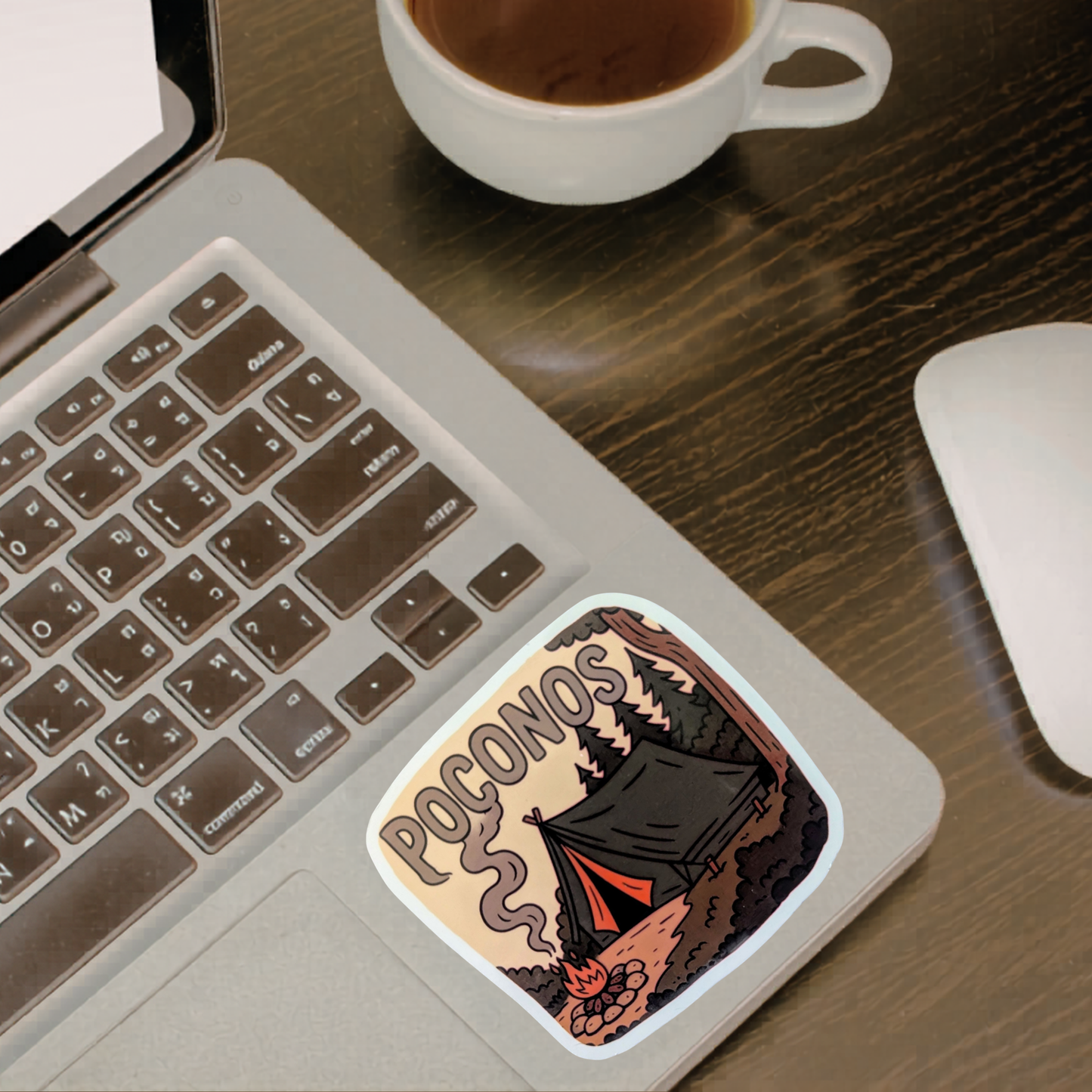 Laptop with a 'Poconos' sticker on a desk with a cup of coffee and mouse.