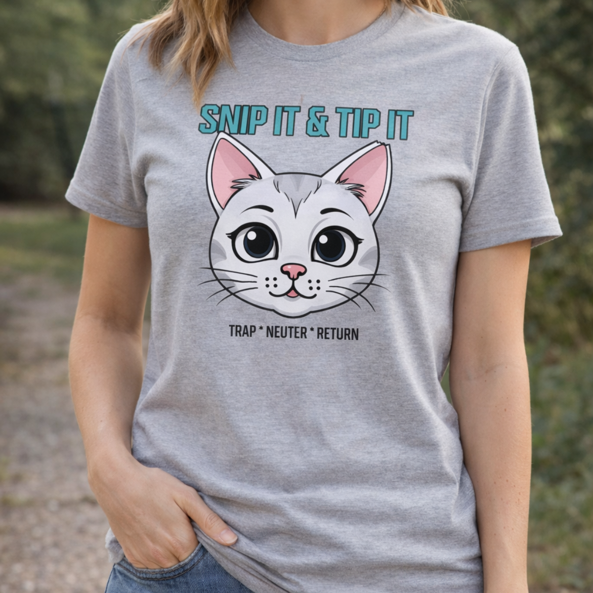 Person wearing a gray t-shirt with a cat graphic and text outdoors.