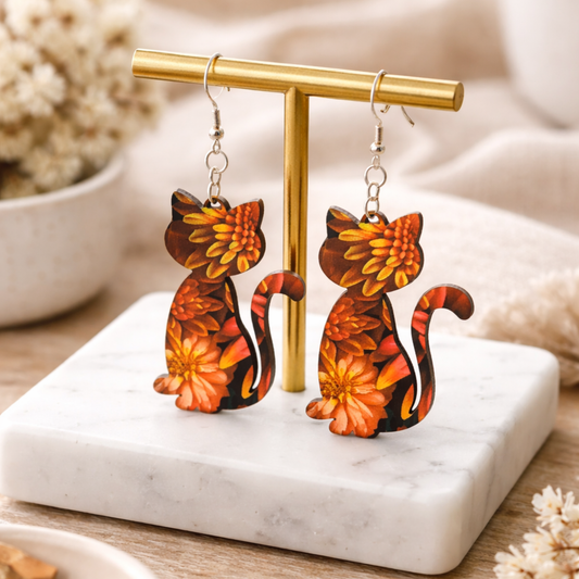 Cat-shaped earrings with floral design on a gold stand with a marble base.