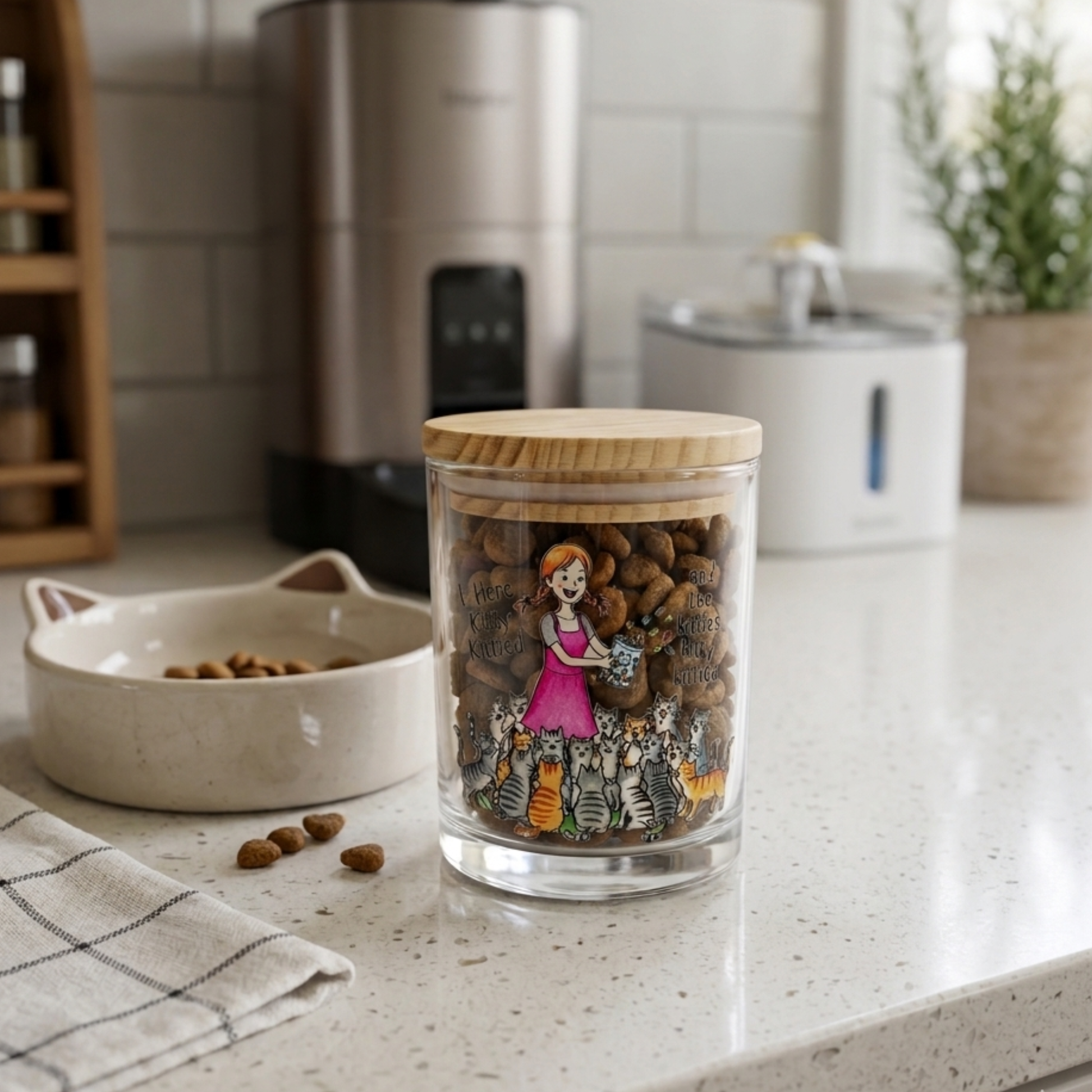 Glass jar with wooden lid on a kitchen counter, filled with cat treats, with a pet bowl and food in the background.