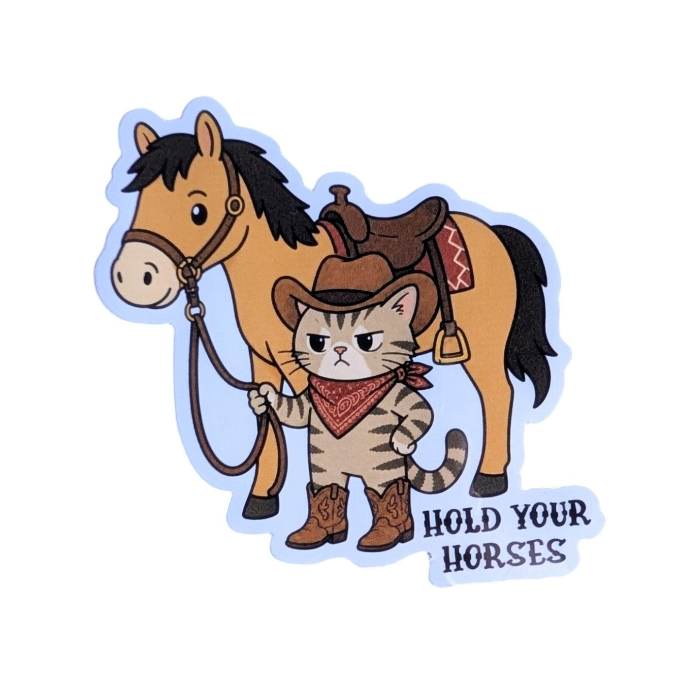 A cartoon die-cut sticker featuring a cat dressed as a cowboy standing in front of a horse, with the text 'HOLD YOUR HORSES' on a white background.