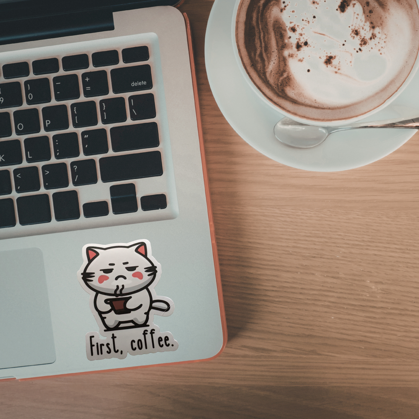 Laptop with a cat sticker and a cup of coffee on a wooden table