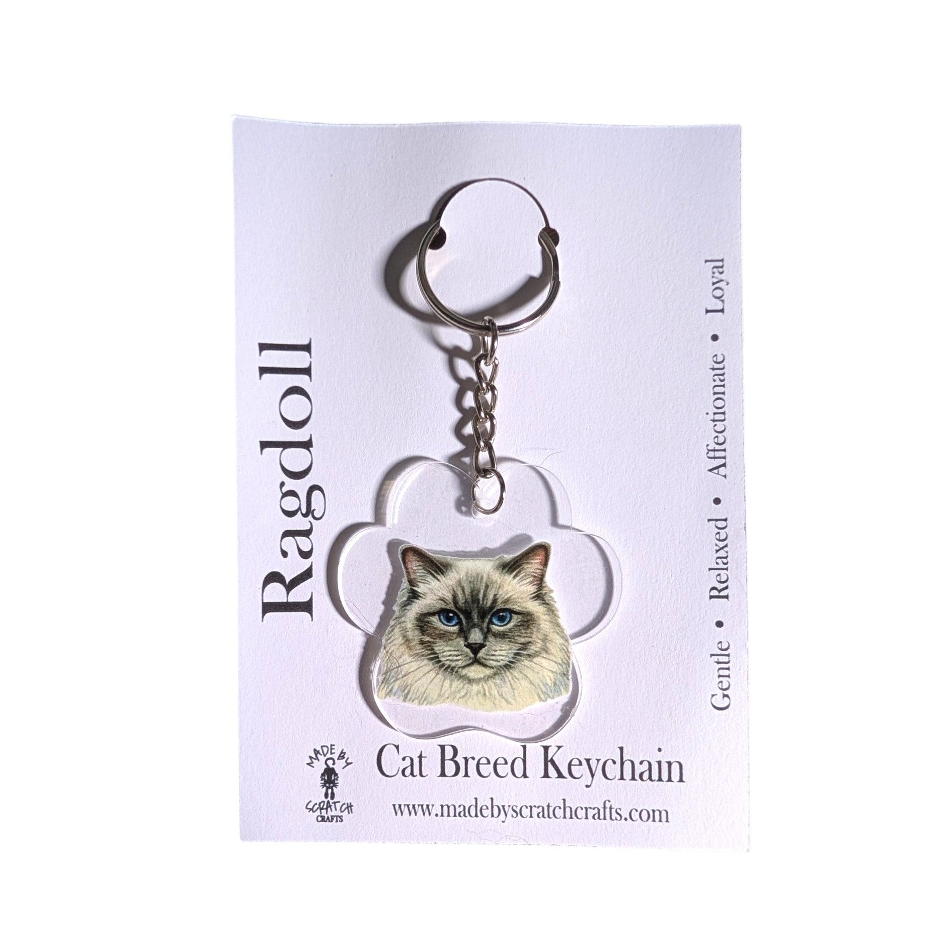 A custom acrylic cat breed keychain featuring a Ragdoll cat portrait, attached to a silver metal key ring and displayed on its white backing card.