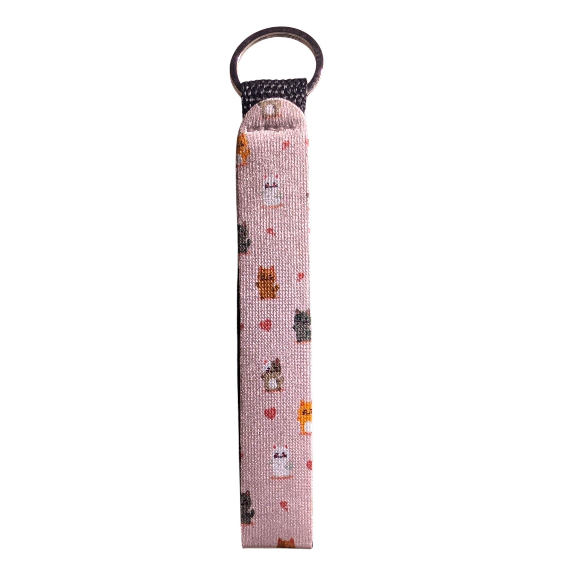 A pink fabric keychain strap featuring a cute pattern of small cartoon cats and hearts, finished with a metal key ring and black woven header.