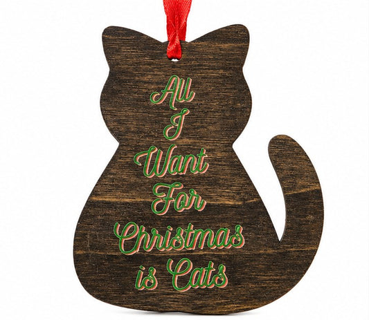 A dark brown wooden cat-shaped Christmas ornament with the phrase 'All I Want For Christmas is Cats' written in green cursive text outlined in red, hanging from a red ribbon on a white background.