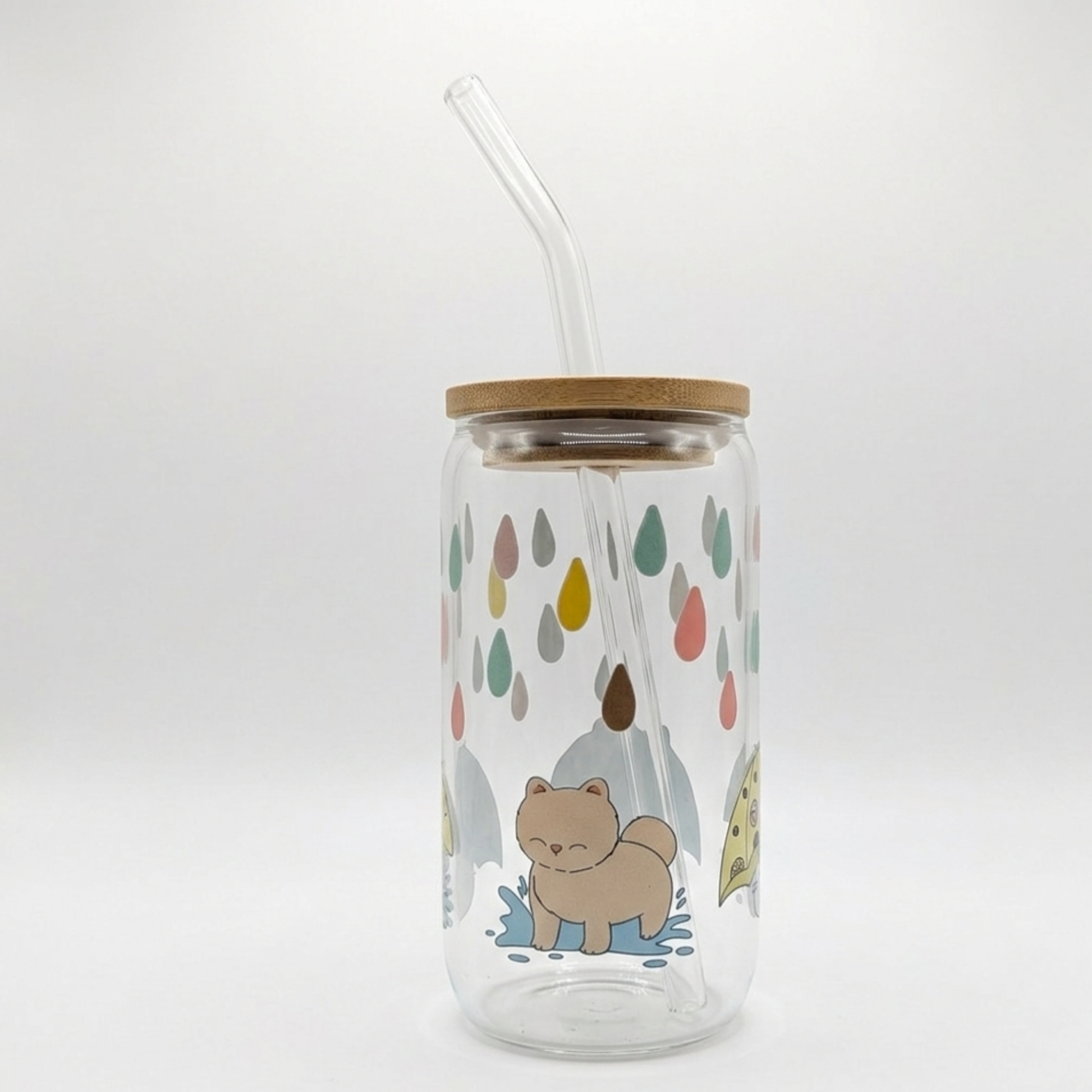 Glass tumbler with wooden lid and straw, featuring a cartoon cat and colorful raindrop design on a white background.