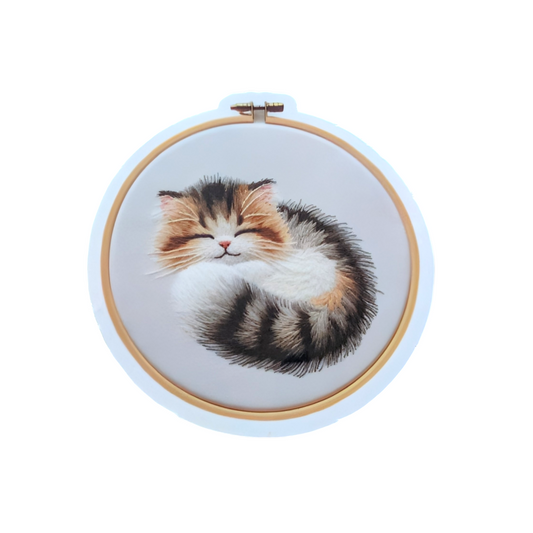 Embroidery hoop with a sleeping cat design on a white background