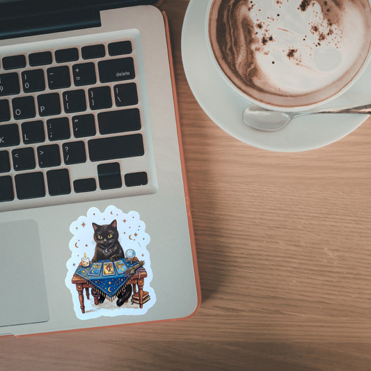 Laptop with a cat sticker on a wooden desk next to a cup of coffee.
