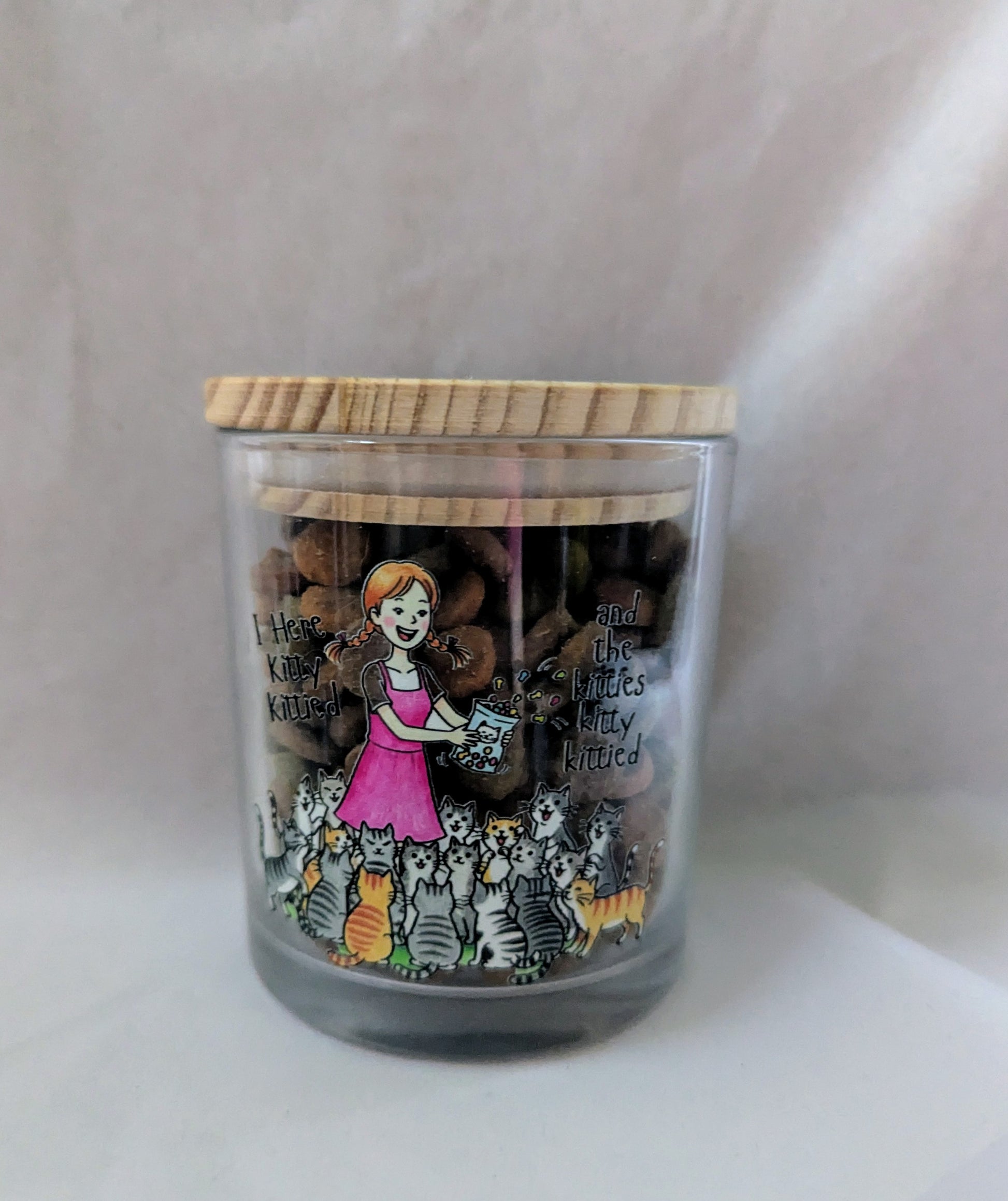 Decorative jar with a wooden lid featuring illustrations of a girl with cats on a white background