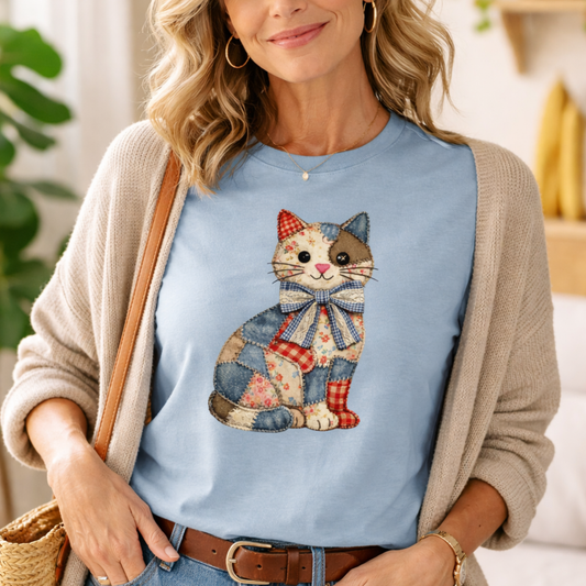 Woman wearing a blue t-shirt with a cat design, standing indoors.