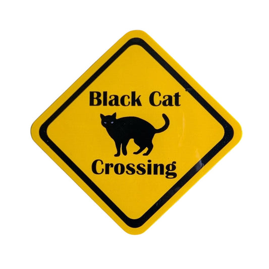 A yellow diamond-shaped sign with a black border, featuring the text 'Black Cat Crossing' and a black cat silhouette in the center, shown on a plain white background.