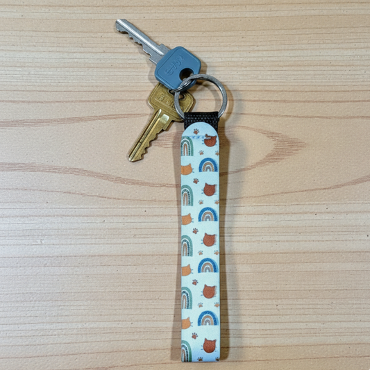 Keychain with rainbow and cat head shape pattern on a wooden surface