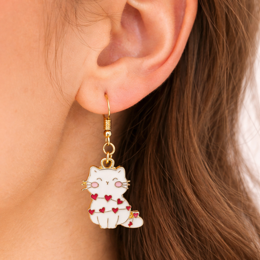 Cat-shaped earring with red hearts worn by a person