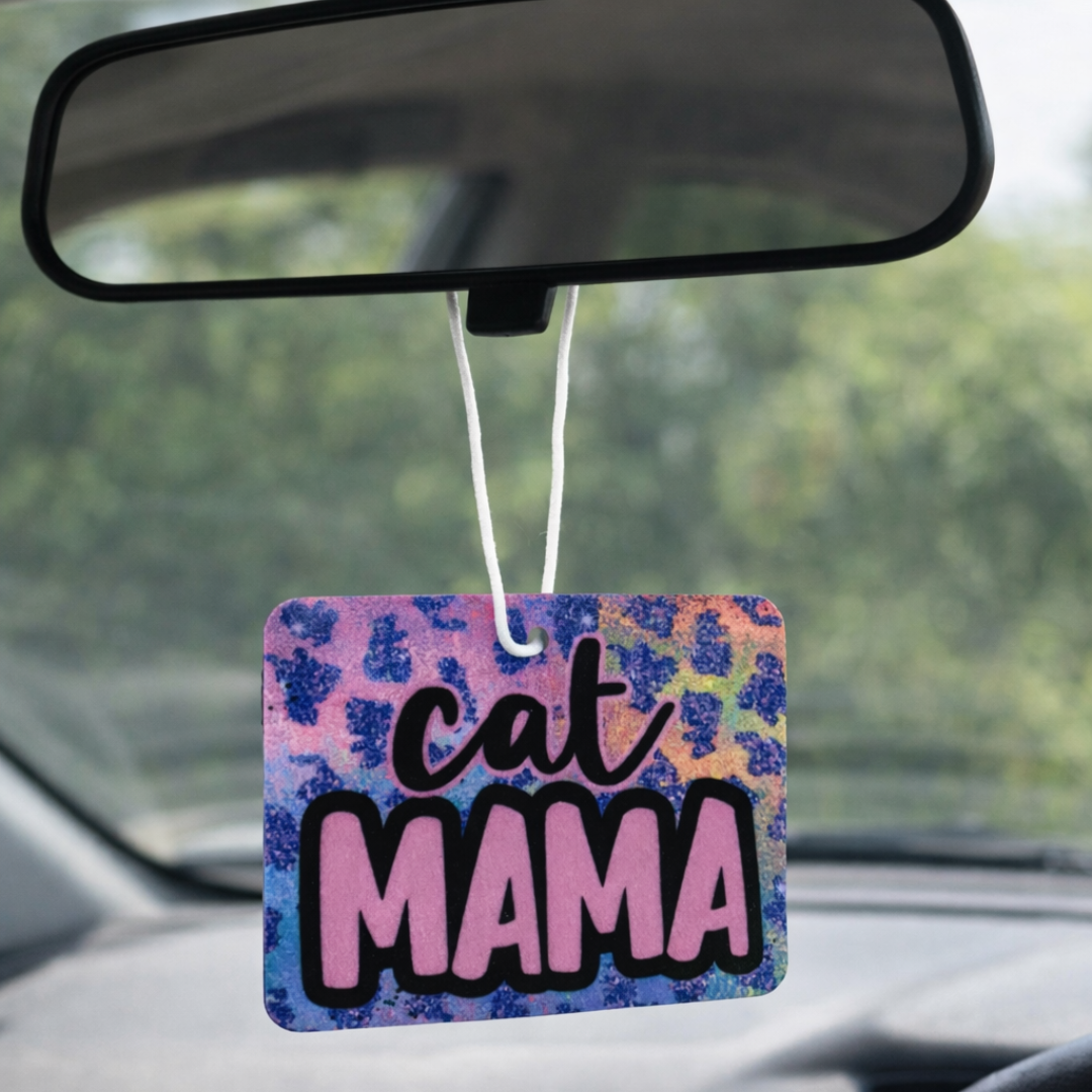 Car air freshener with 'Cat Mama' text hanging from a car's rearview mirror.
