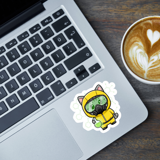 Laptop with a sticker of a cat in a yellow hazmat suit on a wooden surface with a cup of coffee.