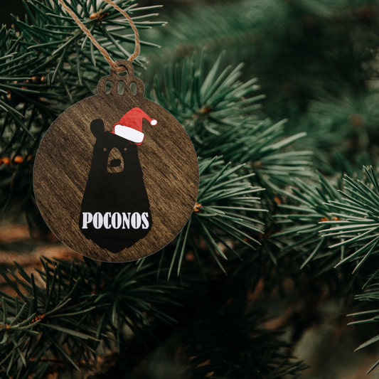 Poconos bear Christmas ornament hanging on a pine tree branch
